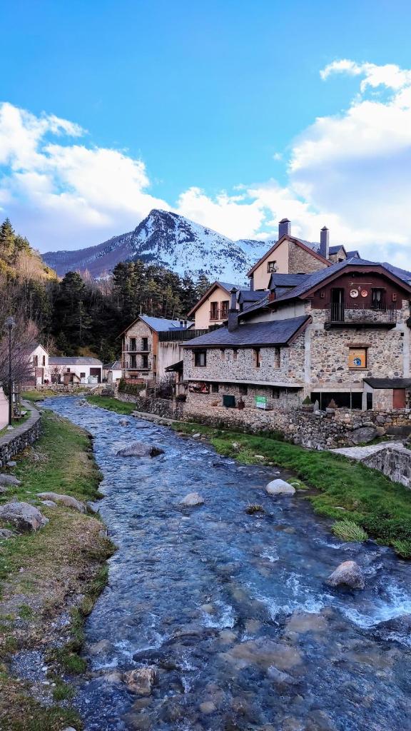 une rivière dans un village avec une montagne en arrière-plan dans l'établissement Appartement chaleureux en cœur de station, à Laruns