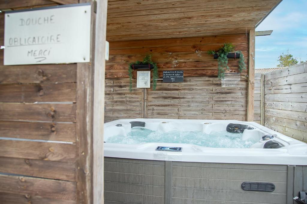 d'un bain à remous dans une arrière-cour avec un mur en bois. dans l'établissement New - Gite Lylou piscine et spa, à Saint-Jean-de-Monts 15 autres photos