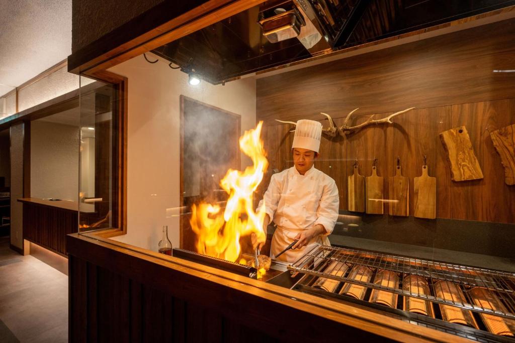 - un chef debout devant un grill avec cheminée dans l'établissement 森の雫RIN MorinoshizukuRIN, à Biei