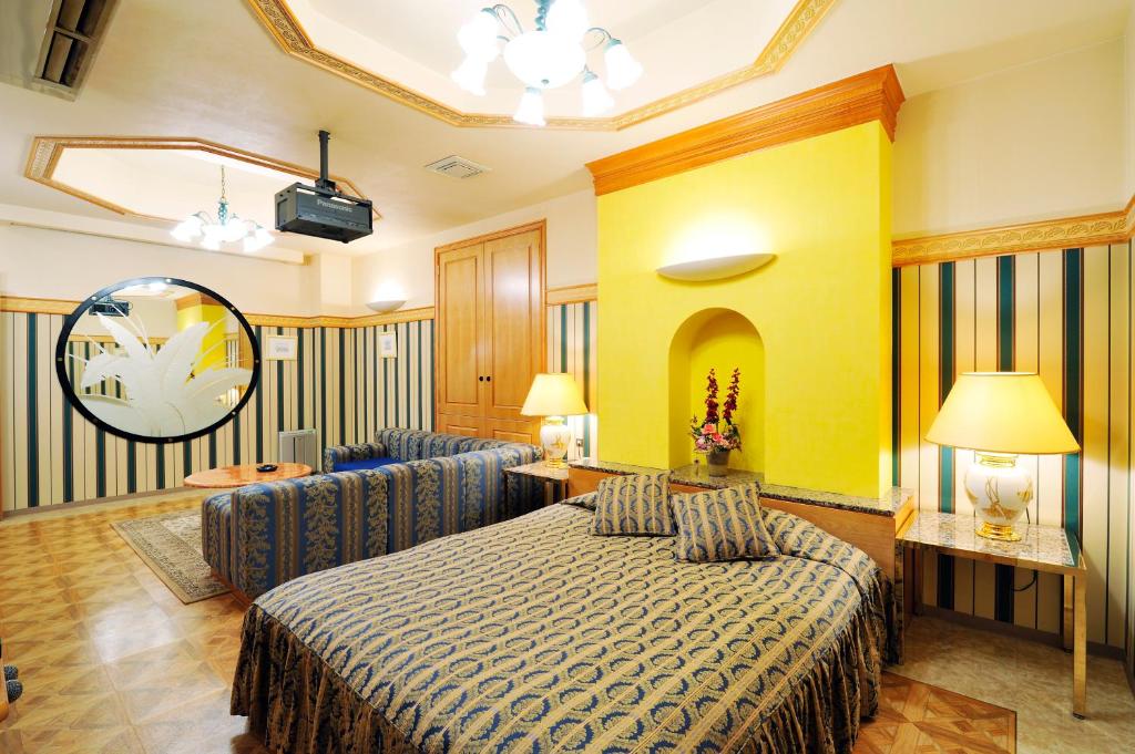 une chambre d'hôtel avec un lit et deux chaises dans l'établissement ホテル　サンタモニカ(大人専用), à Shōmachi