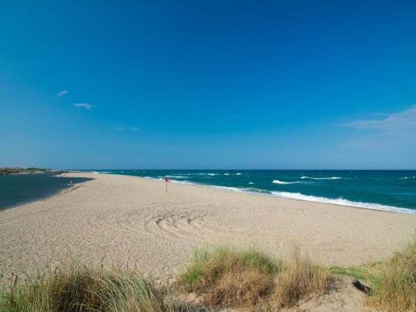 une plage avec une personne debout sur le sable dans l'établissement Mobilhome 6 pers PLAGE À 500M, à Plage dʼArgelès
