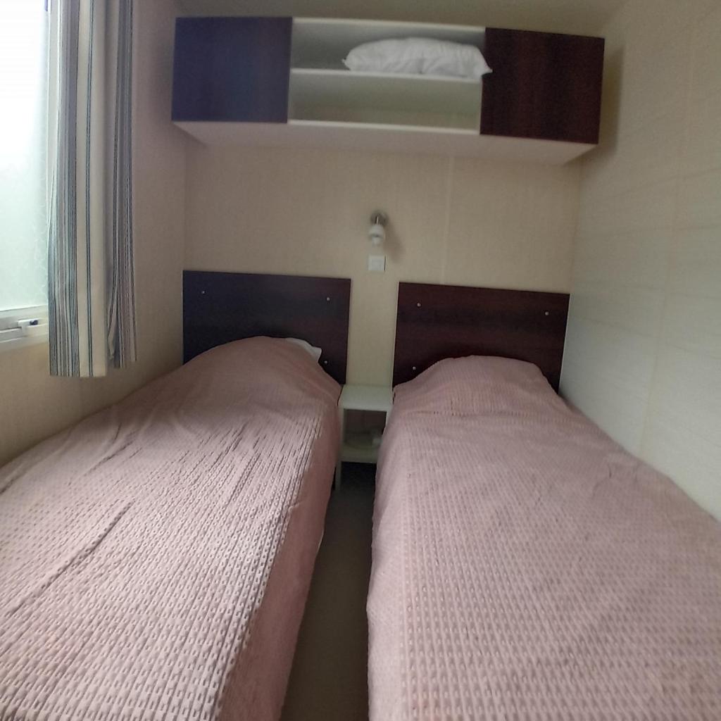- 2 lits dans une petite chambre avec fenêtre dans l'établissement Mobilhome 6 pers PLAGE À 500M, à Plage dʼArgelès