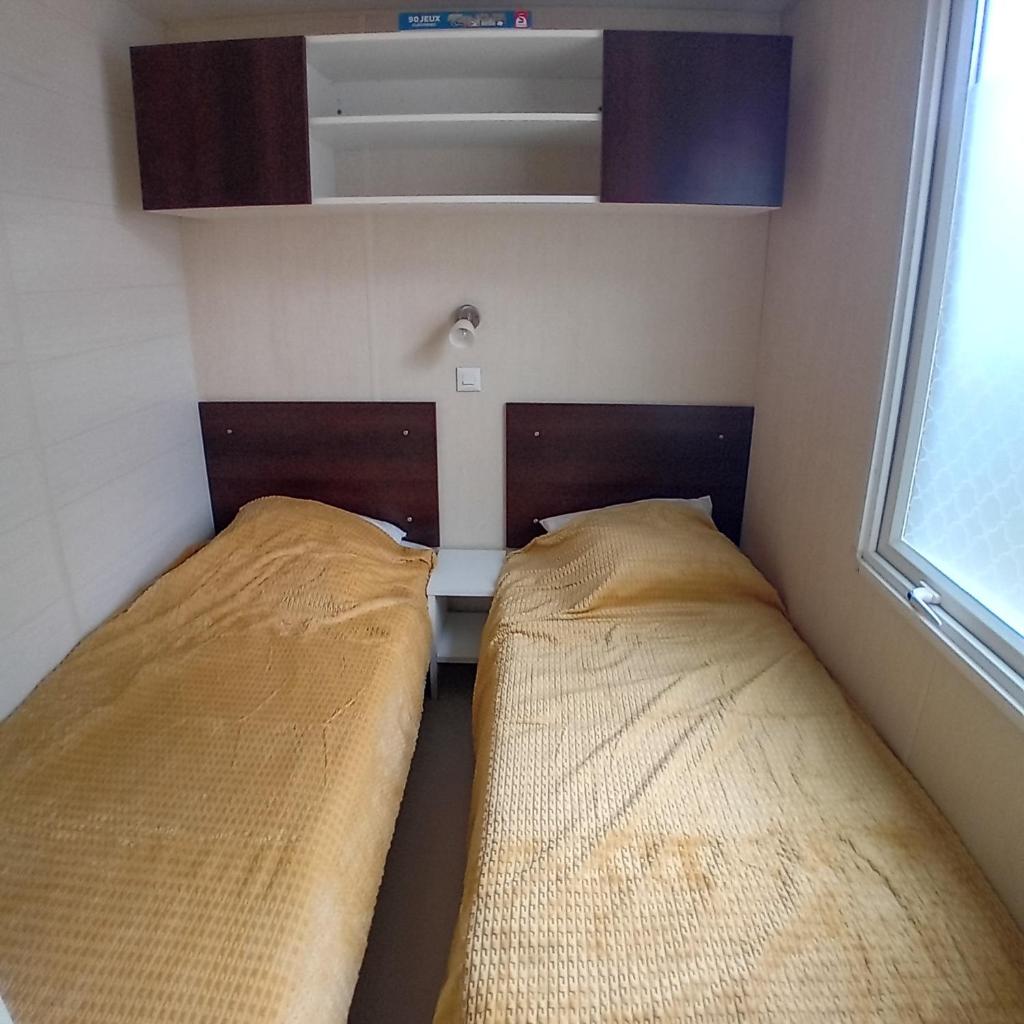 deux lits dans une petite pièce avec une fenêtre dans l'établissement Mobilhome 6 pers PLAGE À 500M, à Plage dʼArgelès 3 autres photos