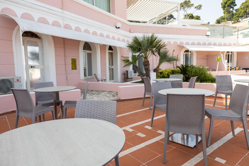 un patio avec des tables et des chaises dans un bâtiment rose dans l'établissement HOTEL SOLE, à San Menaio