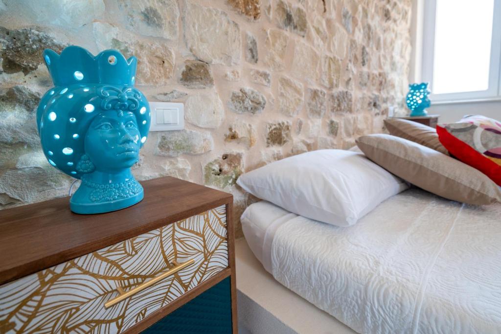 un vase bleu assis sur une table à côté d'un lit dans l'établissement Villa Domus Sicilia - Charming Living, à Modica 62 autres photos
