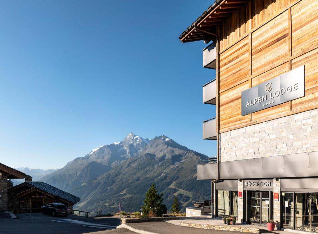 un bâtiment avec une montagne en arrière-plan dans l'établissement MGM Hôtels & Résidences - Résidence Alpen Lodge, à La Rosière 37 autres photos