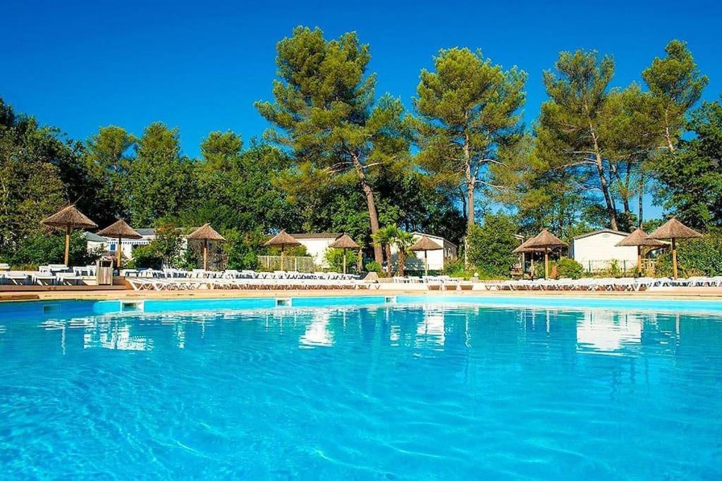 une grande piscine avec chaises et parasols dans l'établissement MOBILHOME PREMIUM 3CH 6PERS, à Nans-les-Pins
