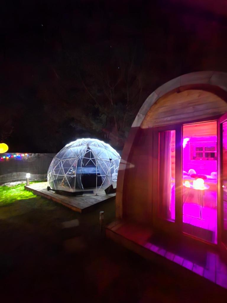un igloo avec des lumières violettes la nuit dans l'établissement Magnifique Pod avec spa sous bulle privatif, à Lanthenay