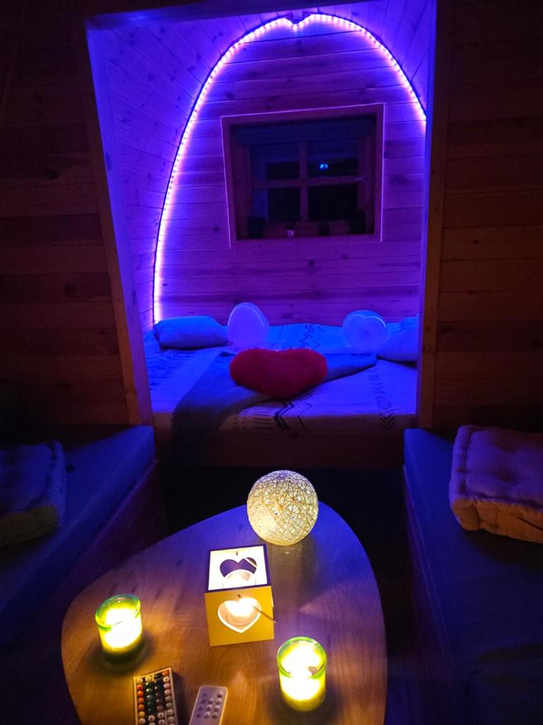 Cette chambre est dotée d'un éclairage violet et d'une table. dans l'établissement Magnifique Pod avec spa sous bulle privatif, à Lanthenay