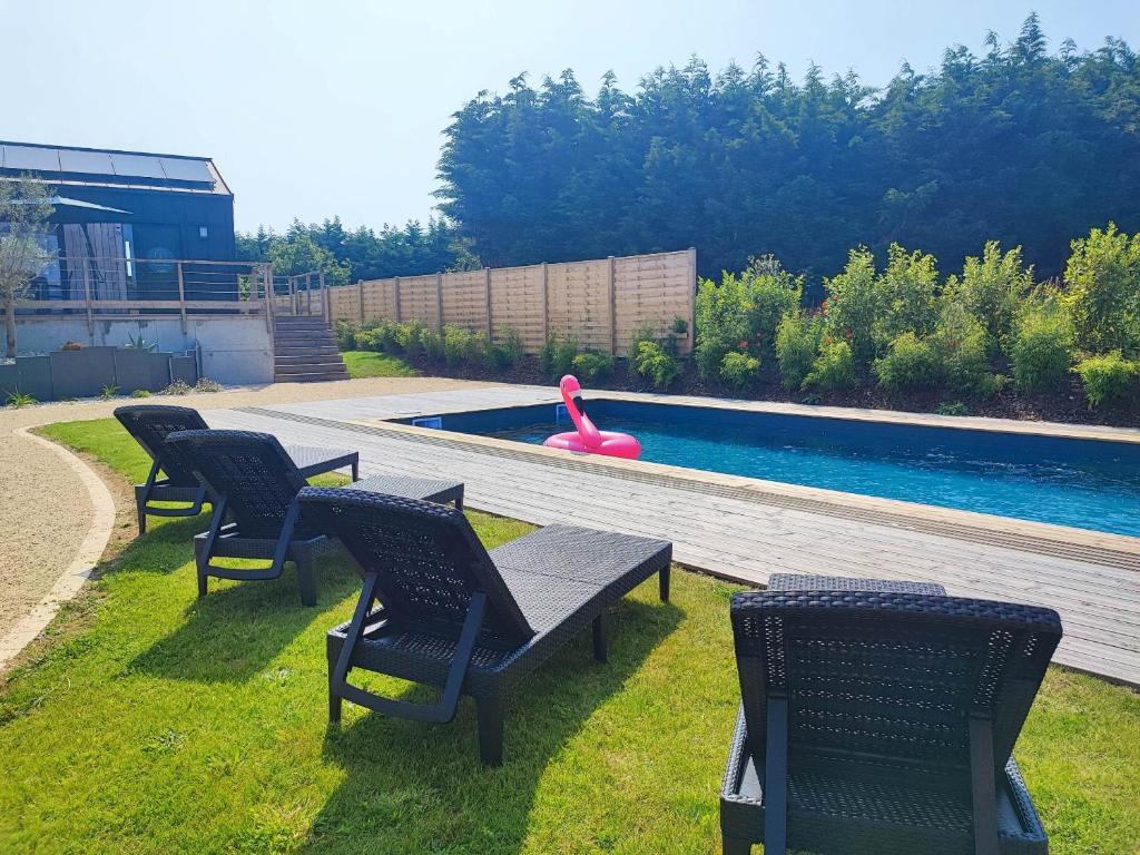 un groupe de chaises assises à côté d'une piscine dans l'établissement Les suites du littoral - Gîtes proche mer - Piscine - SPA, à Plouézec
