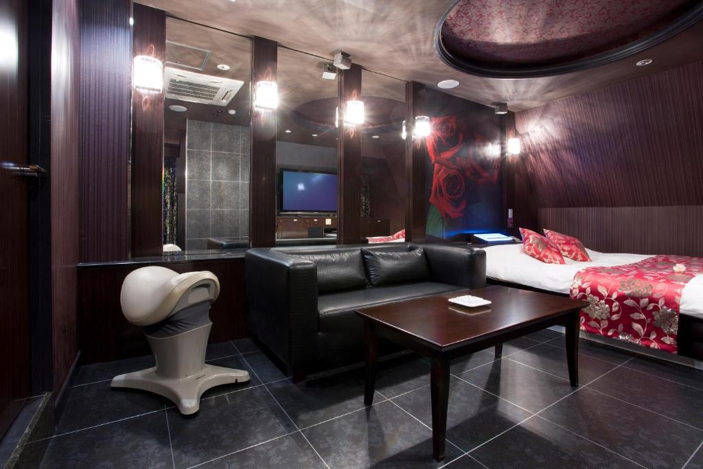 Cette chambre comprend un lit, un canapé et une table. dans l'établissement もしもしピエロ NEO 京都店, à Kyoto