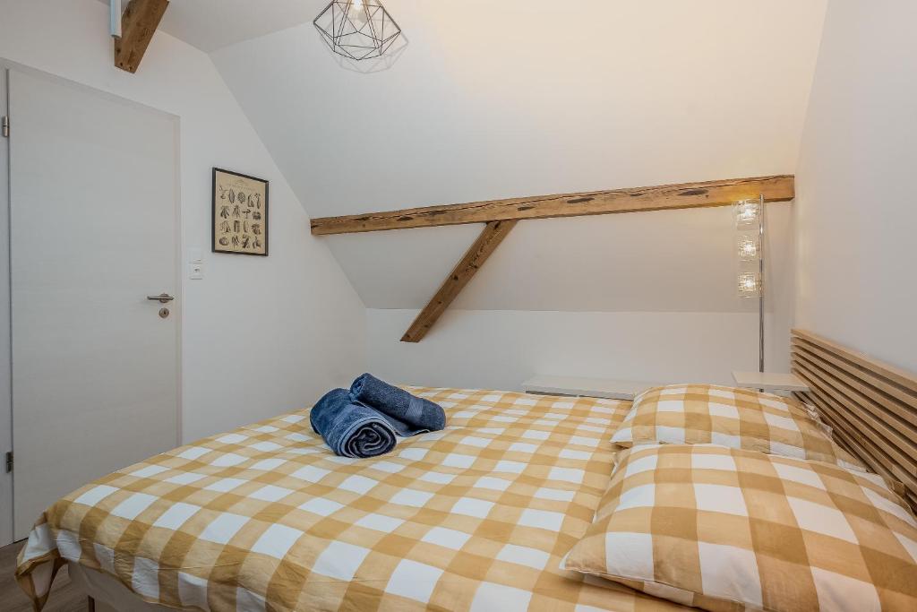 une chambre avec un lit avec une couverture à carreaux dans l'établissement Une petite vue sur le Paradis, à Orbey