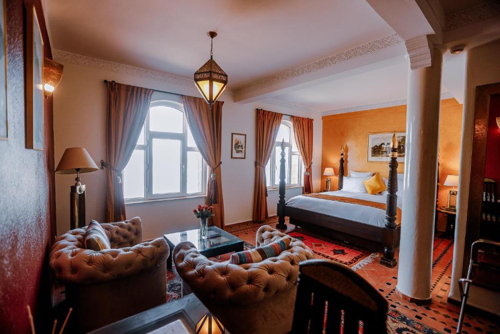 une chambre avec un lit, une table et des chaises dans l'établissement Riad Perle D'Eau, à Essaouira