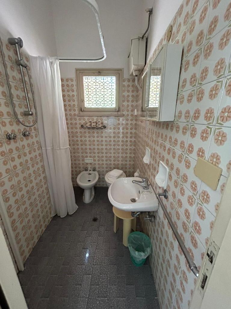 une salle de bain avec un lavabo, des toilettes et un miroir dans l'établissement Camere Capinera, à Cesenatico