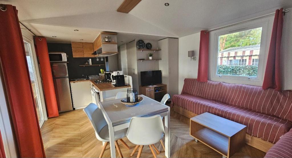un salon avec un canapé rouge et une table dans l'établissement Mobilhome N°222 : 3ch / 2sdb dans camping 4*, à Gastes