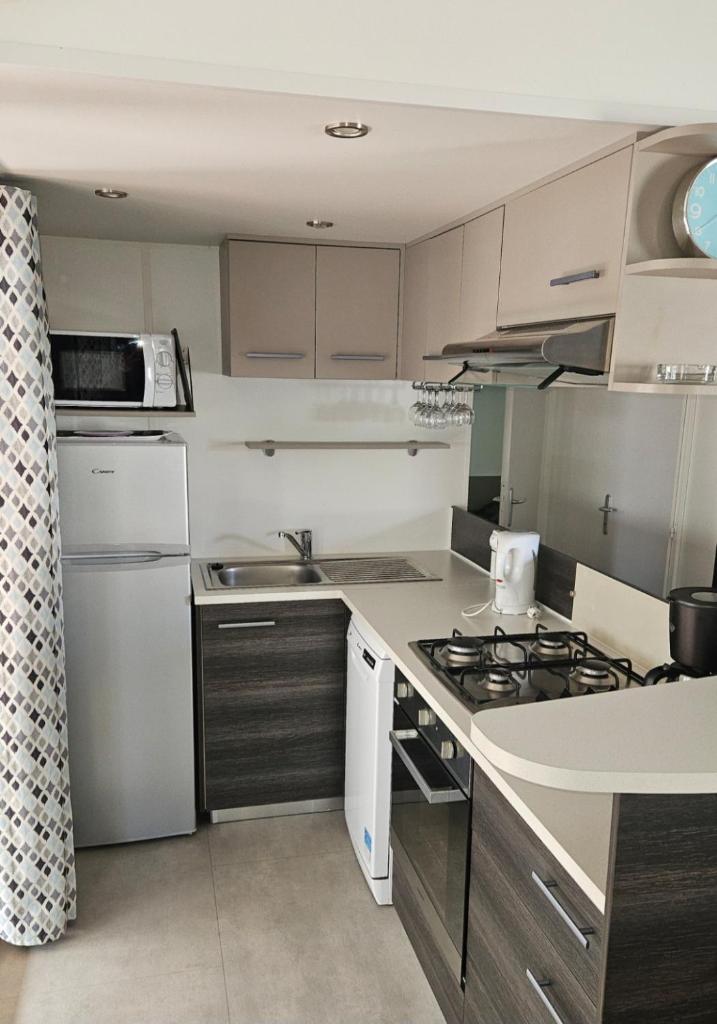 une cuisine avec un évier et une cuisinière four supérieur dans l'établissement Grand mobil-home n°604 3ch tout confort au calme, à Gastes 10 autres photos