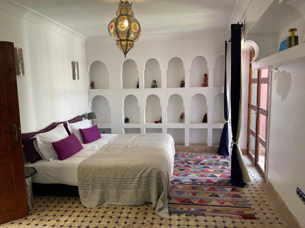 - une chambre avec un lit doté d'oreillers violets et d'un lustre dans l'établissement Riad Tafilag, à Taroudant