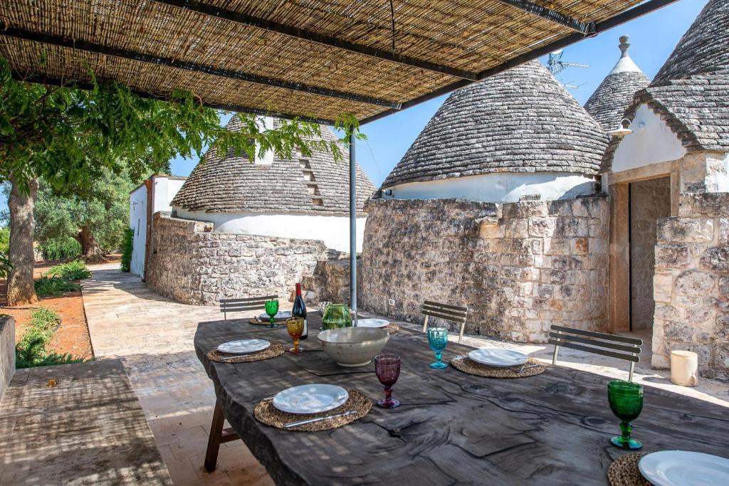 - une table avec des assiettes et des verres à vin sur la terrasse dans l'établissement Tenuta Diciassetteconi Trulli With Pool, à Ostuni