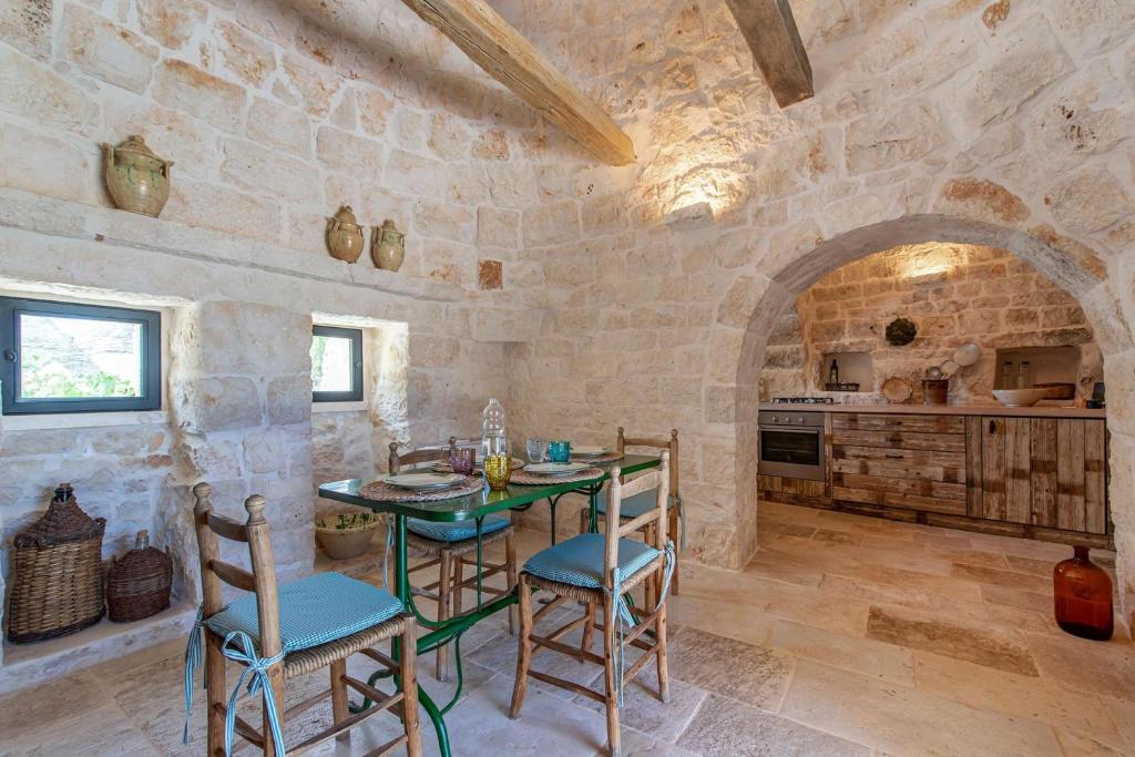 une salle à manger avec une table et des chaises et un mur en pierre dans l'établissement Tenuta Diciassetteconi Trulli With Pool, à Ostuni