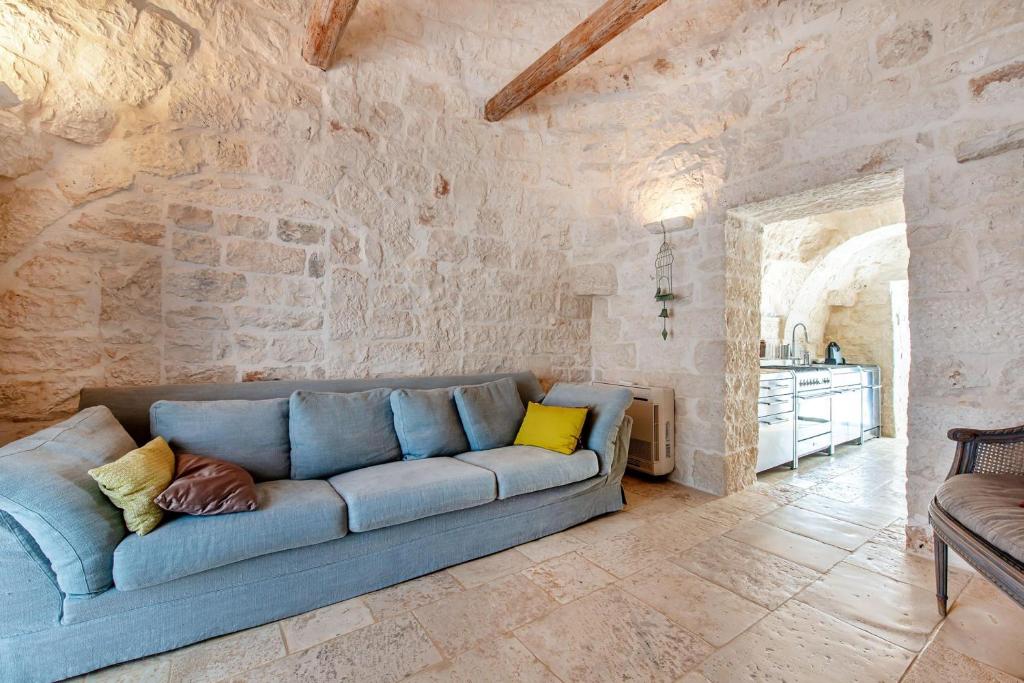 - un canapé bleu dans une chambre avec un mur en pierre dans l'établissement Tenuta Diciassetteconi Trulli With Pool, à Ostuni