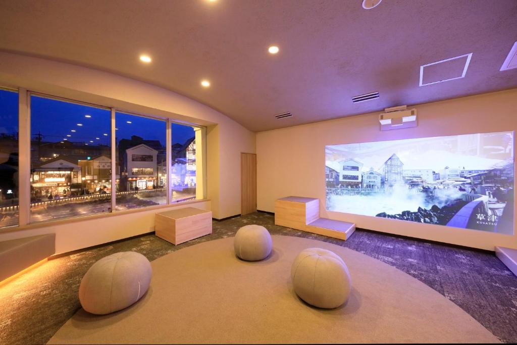 un salon avec une grande fenêtre avec des poufs blancs dans l'établissement Hotel Ichii, à Kusatsu