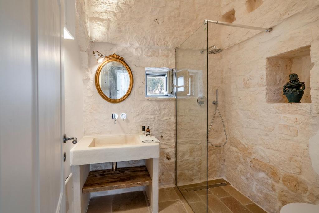 une salle de bain avec un lavabo et une douche dans l'établissement Trullo Saraceno, à Ostuni