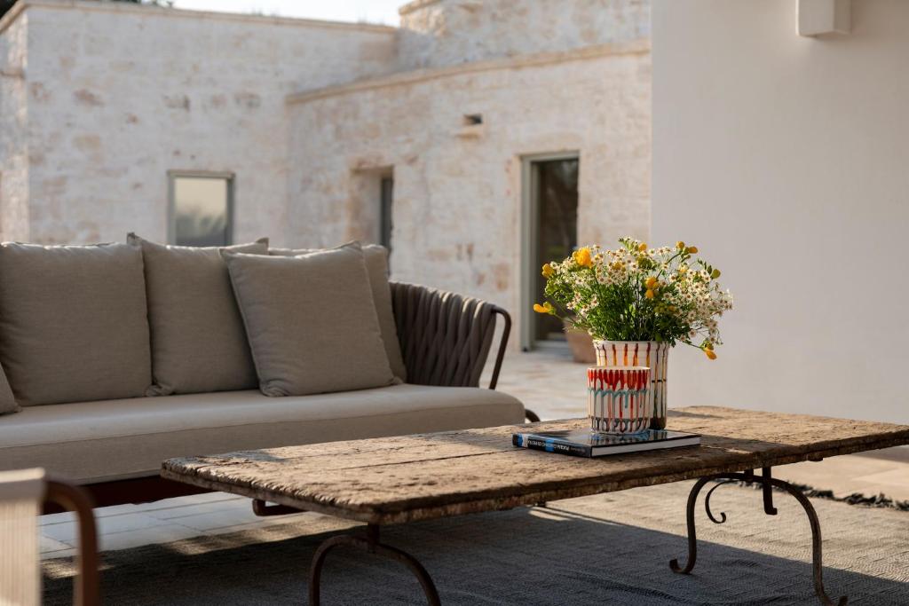 un salon avec un canapé et une table avec des fleurs dans l'établissement Trullo Saraceno, à Ostuni