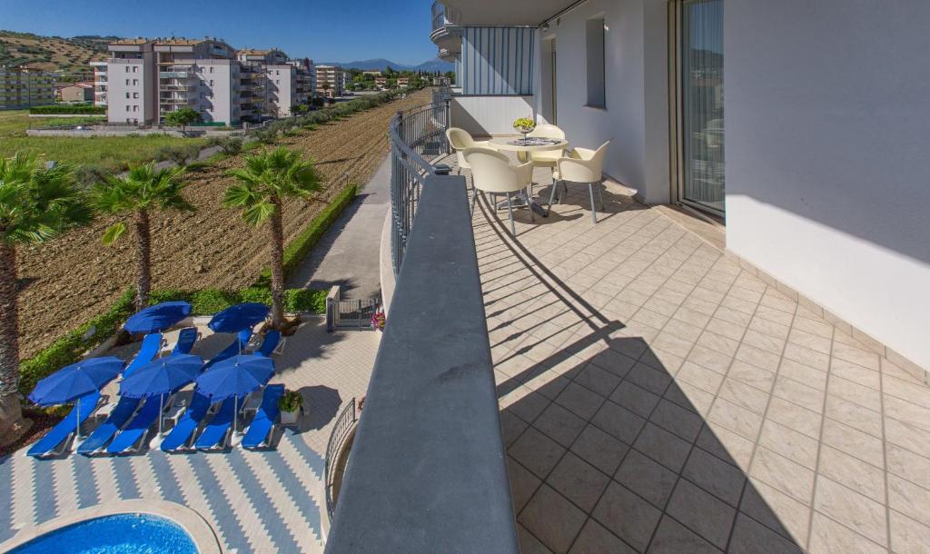 d'un balcon avec des chaises bleues et une table avec des parasols. dans l'établissement Residence il Girasole 1, à Alba Adriatica