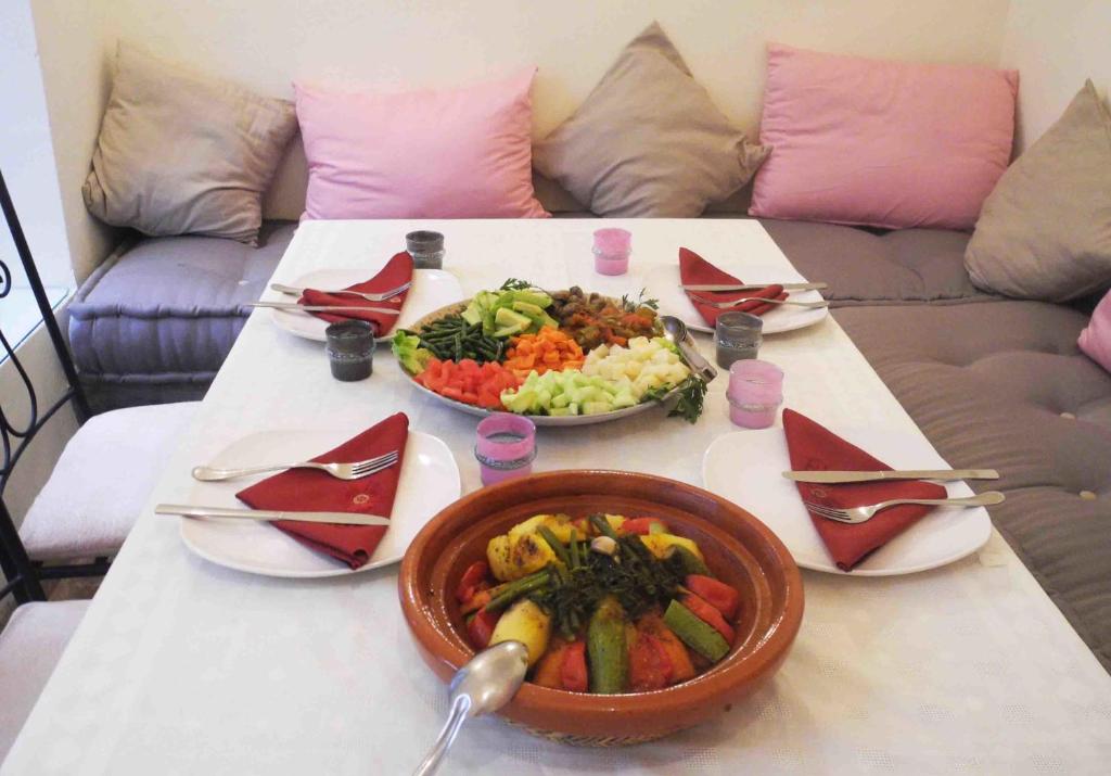 une table avec deux assiettes de nourriture et un bol de légumes dans l'établissement Riad Linda, à Marrakech