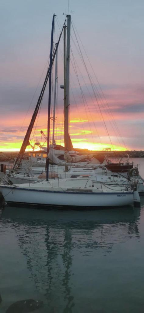 un voilier amarré dans l'eau avec un coucher de soleil en arrière-plan dans l'établissement Voilier en bord de mer 55€ par nuit, à Marseillan
