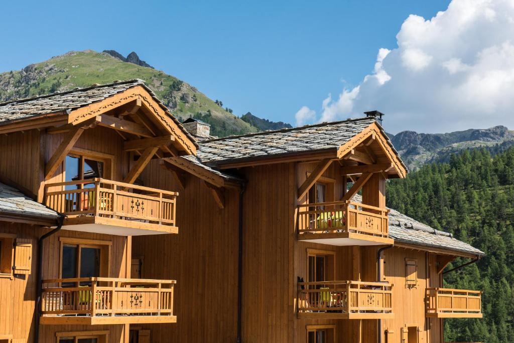 une cabane en rondins avec balcon et montagnes en arrière-plan dans l'établissement CGH Résidences & Spas Le Chalet des Dolines, à Montgenèvre