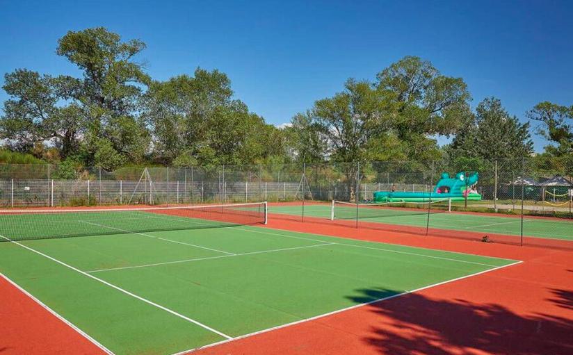 un court de tennis avec une aire de jeux en arrière-plan dans l'établissement Mobile Home 270, à La Roque-dʼAnthéron