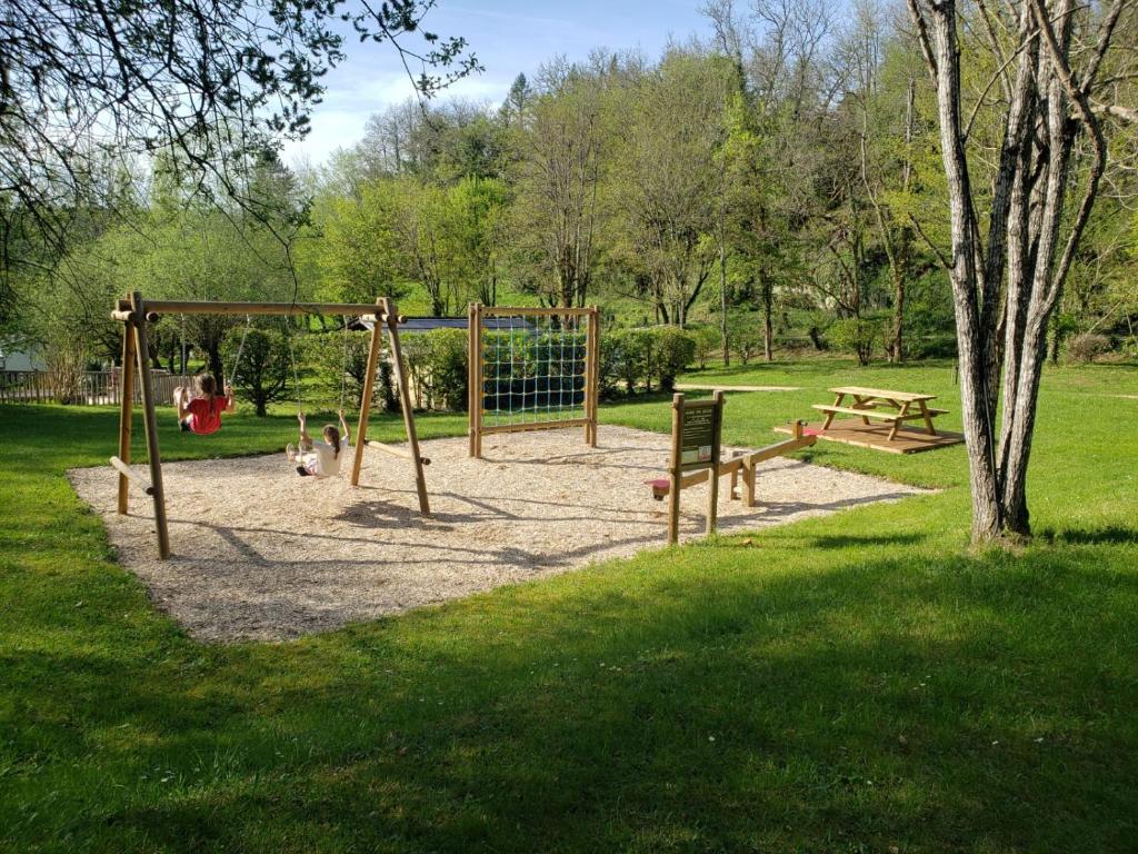 un parc avec une aire de jeux et une balançoire dans l'établissement Camping EAU NATURELLE 2 étoiles Bungalow ou Tente 4 personnes dans un environnement calme et dépaysant, à Tursac