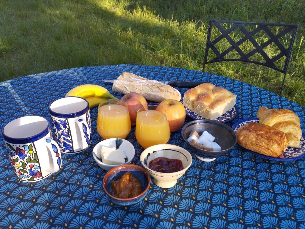 une table bleue recouverte de différents types de pain et de jus d'orange dans l'établissement La yourte kirghize, à Alès