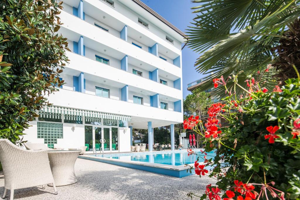 un hôtel avec une piscine et des fleurs dans l'établissement Hotel Olympia, à Lignano Sabbiadoro