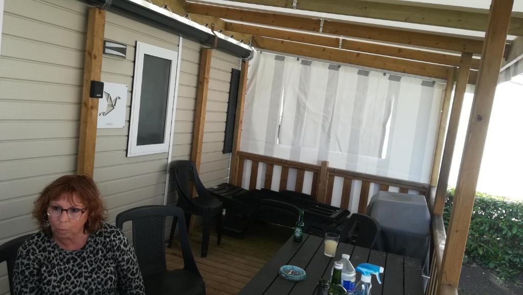 une femme assise à une table sur un patio dans l'établissement Superbe Mobil home 3 chambres F51, à Saint-Jean-de-Monts