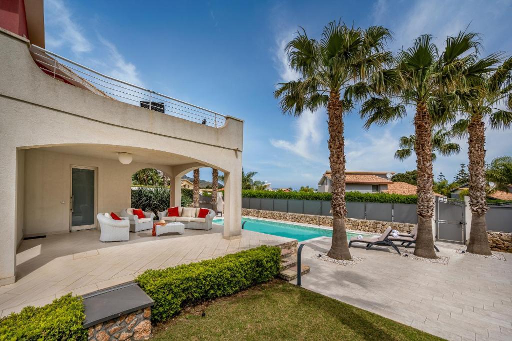 une cour avec une piscine et des palmiers dans l'établissement Villa Jacqueline con piscina privata 8 posti letto, à Scopello