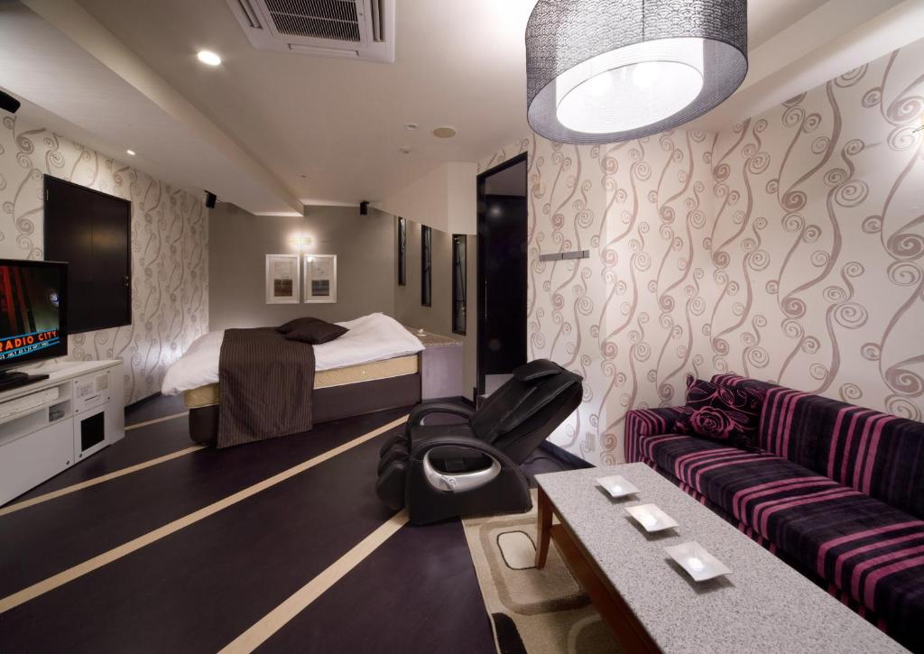 une chambre d'hôtel avec un lit et un canapé dans l'établissement HOTEL & SPA ISLAND (Adult Only), à Toyota