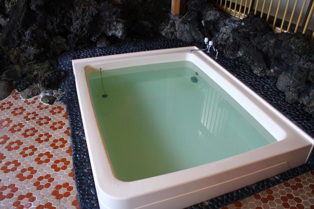 une grande baignoire installée sur un sol carrelé dans l'établissement Kinokuniya Ryokan, à Fujisawa