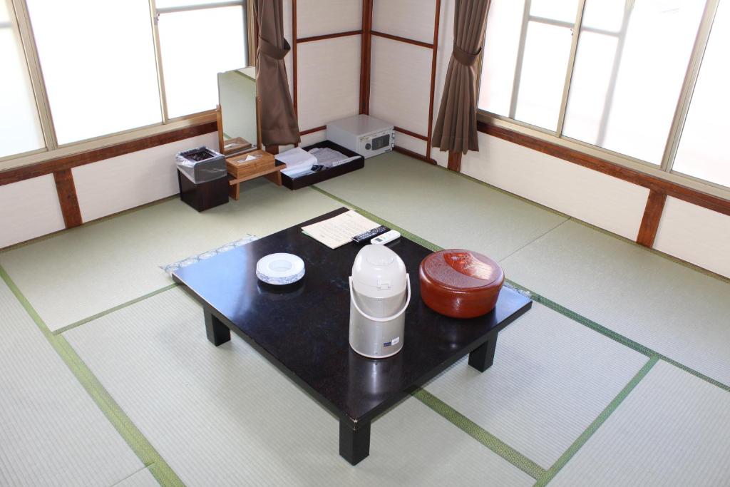 Cette chambre dispose d'une table basse avec une carafe. dans l'établissement Kinokuniya Ryokan, à Fujisawa