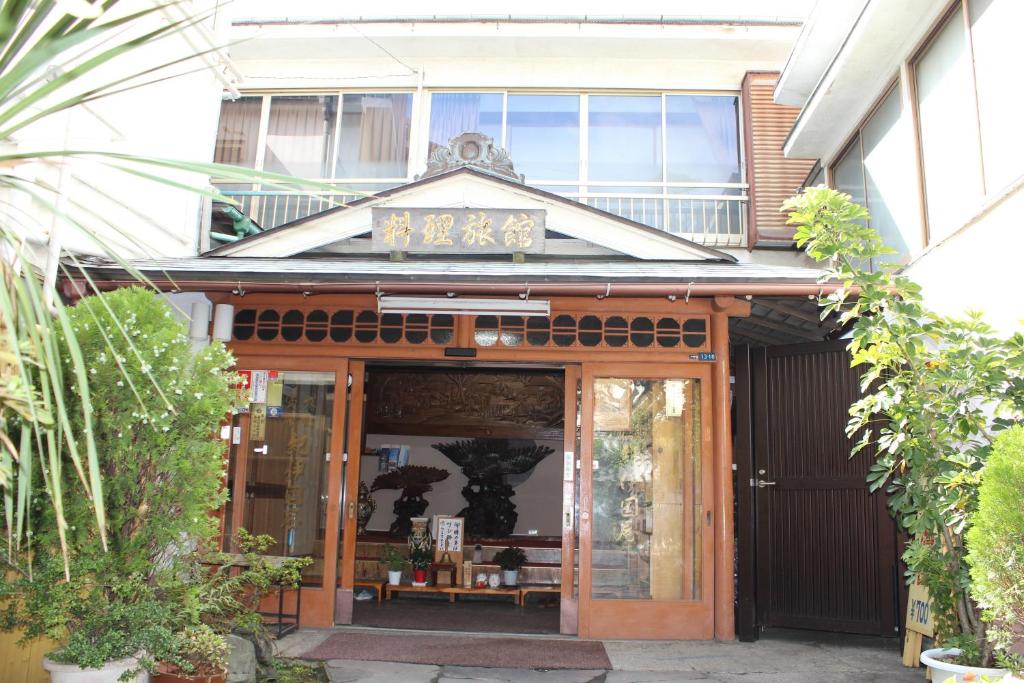 un bâtiment avec une enseigne au sommet dans l'établissement Kinokuniya Ryokan, à Fujisawa