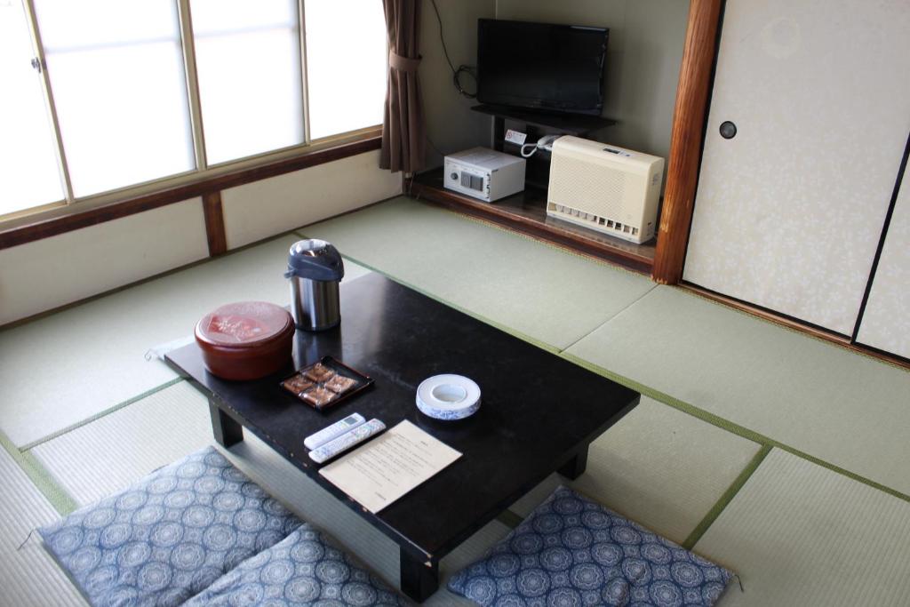 Cette chambre dispose d'une table et d'une télévision. dans l'établissement Kinokuniya Ryokan, à Fujisawa