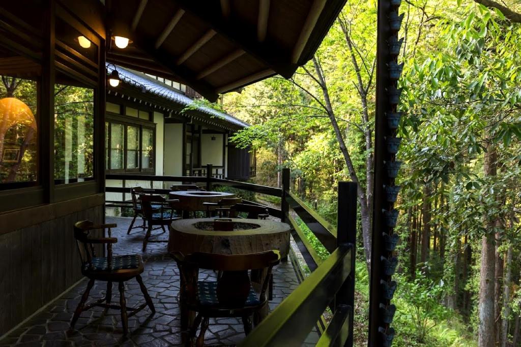 un patio extérieur avec des tables, des chaises et des arbres dans l'établissement Hazu Gassyo, à Shinshiro