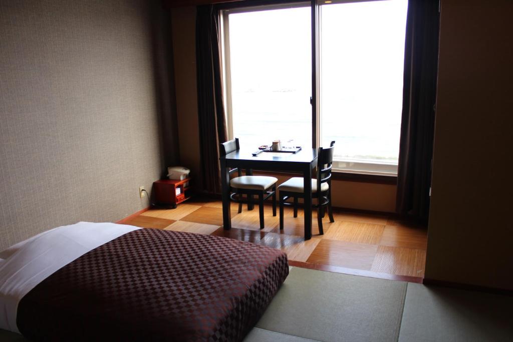 - une chambre avec une table, des chaises et une fenêtre dans l'établissement Hotel Shiosai, à Fujisawa