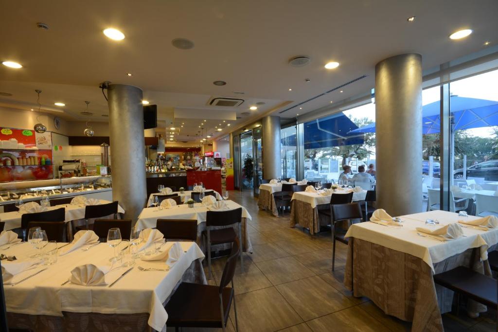une salle à manger avec des tables et des chaises blanches et un restaurant dans l'établissement Kiara Residence, à Giulianova