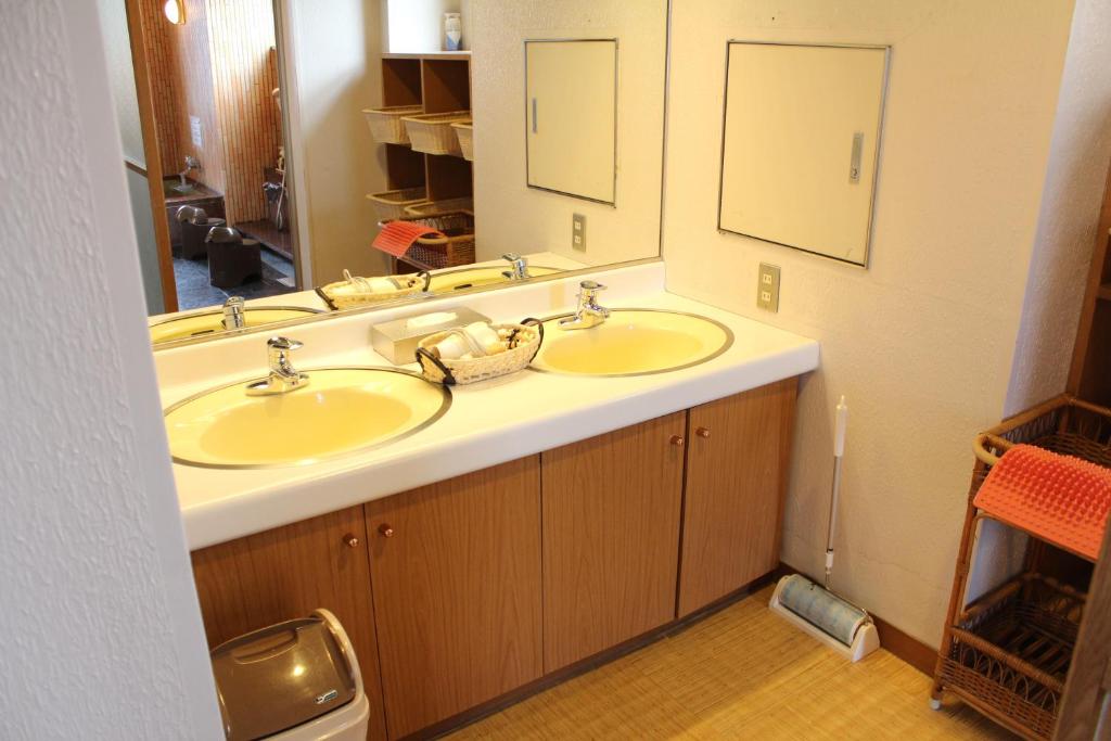 une salle de bain avec deux lavabos et un grand miroir dans l'établissement Hotel Shiosai, à Fujisawa
