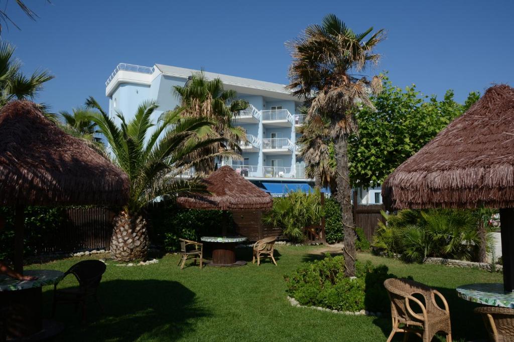un complexe avec des tables, des chaises et des palmiers dans l'établissement Kiara Residence, à Giulianova