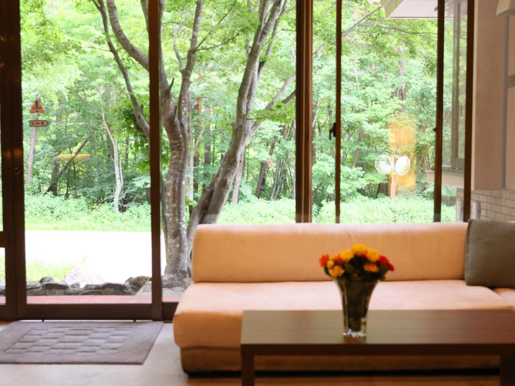 un salon avec un canapé et une table avec des fleurs dans l'établissement Kamikochi Hotel, à Matsumoto