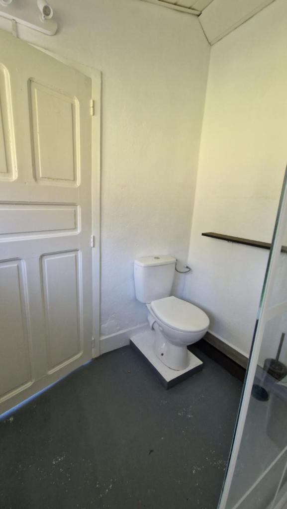 La salle de bains est pourvue de toilettes blanches et d'une porte. dans l'établissement De pipowagens van het Château, à Viviez