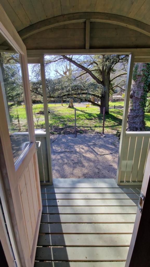 une porte ouverte d'une maison avec une terrasse couverte dans l'établissement De pipowagens van het Château, à Viviez